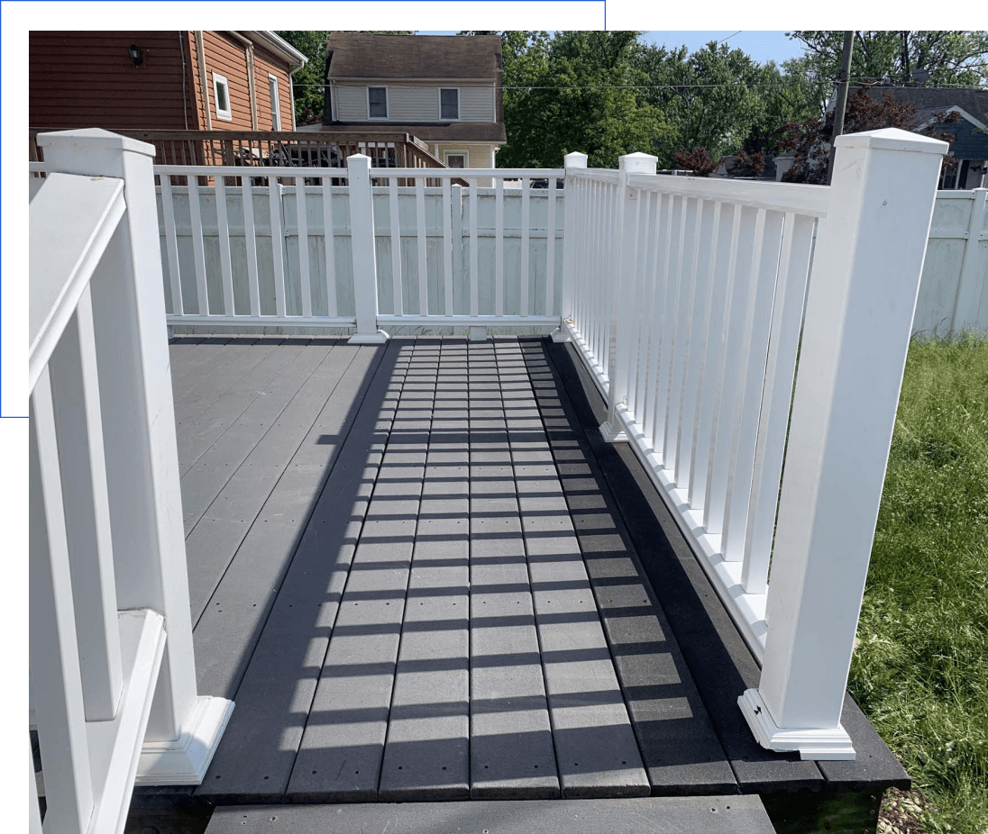 Ramped deck with white railing, backyard view.